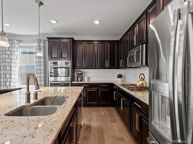 5439 Verbena St, Denver, CO 80238 - kitchen with stainless steel appliances, a sink, light wood finished floors, light stone countertops, and pendant lighting