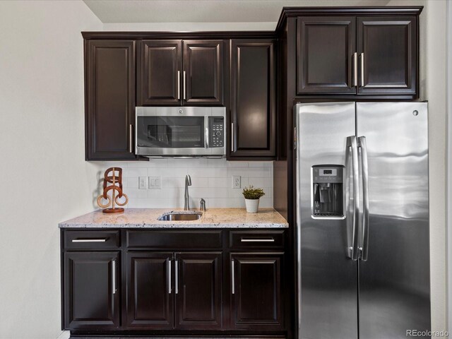5439 Verbena St, Denver, CO 80238 - kitchen featuring stainless steel appliances, a sink, backsplash, light stone countertops, and dark brown cabinetry