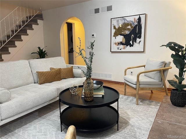 living room with visible vents, wood finished floors, stairway, arched walkways, and baseboards