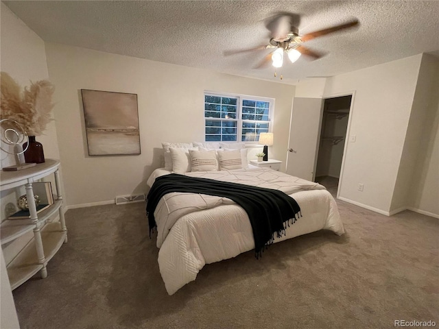 carpeted bedroom featuring a spacious closet, a textured ceiling, ceiling fan, and a closet