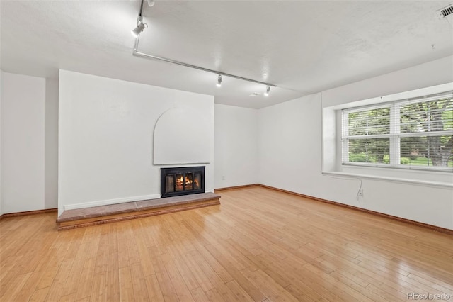 unfurnished living room featuring light hardwood / wood-style flooring and rail lighting