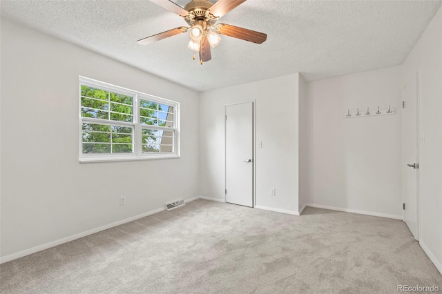 spare room with light colored carpet, a textured ceiling, and ceiling fan