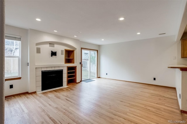 unfurnished living room with recessed lighting, visible vents, light wood-style flooring, a tile fireplace, and baseboards