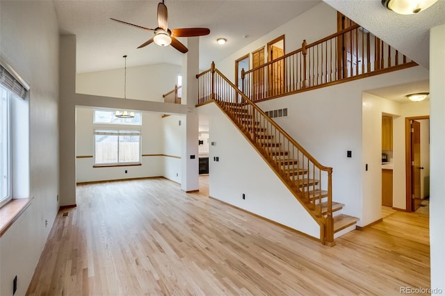 unfurnished living room with baseboards, visible vents, stairway, and light wood finished floors