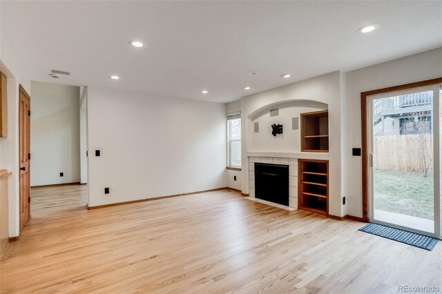 unfurnished living room with light wood-style floors, a fireplace, baseboards, and recessed lighting