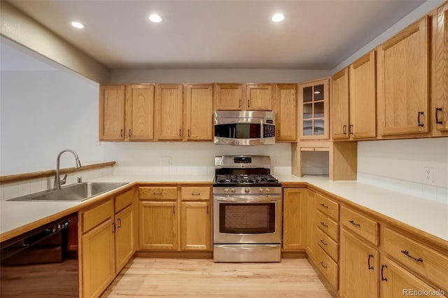 kitchen featuring light wood-style floors, appliances with stainless steel finishes, light countertops, and a sink