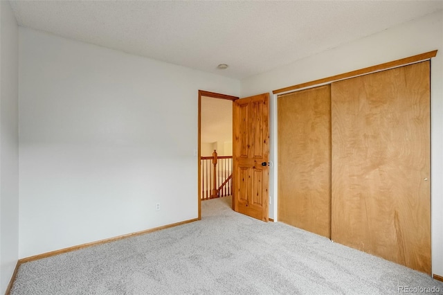 unfurnished bedroom featuring a closet, carpet flooring, a textured ceiling, and baseboards