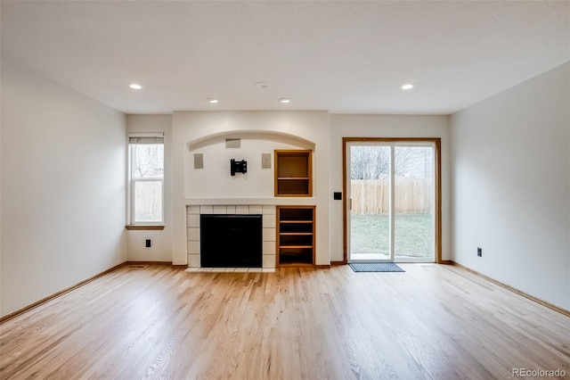 unfurnished living room featuring wood finished floors, a wealth of natural light, and baseboards