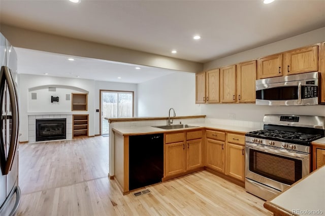 kitchen with visible vents, appliances with stainless steel finishes, open floor plan, a sink, and a peninsula