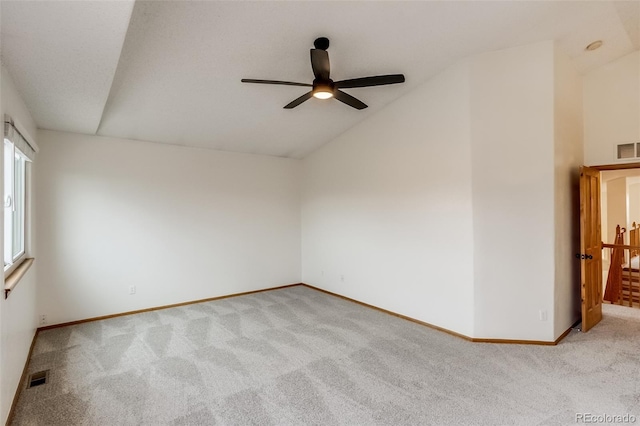 carpeted empty room with lofted ceiling, a ceiling fan, visible vents, and baseboards