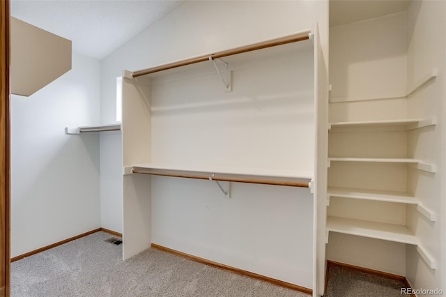 walk in closet with vaulted ceiling, carpet flooring, and visible vents