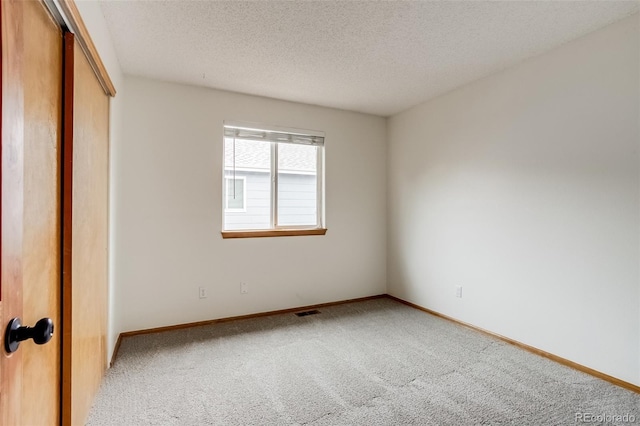 unfurnished bedroom with baseboards, visible vents, carpet, a textured ceiling, and a closet