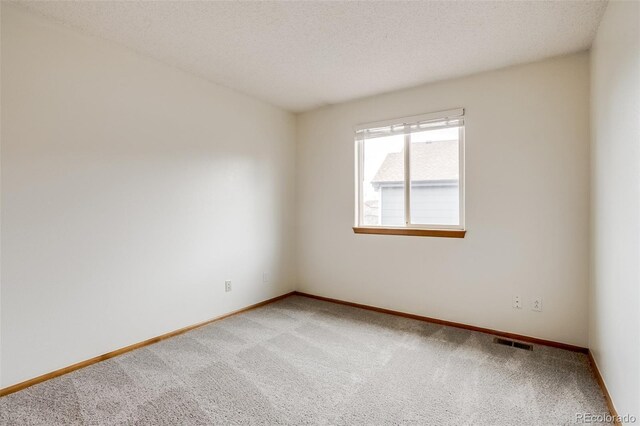 unfurnished room featuring baseboards, visible vents, a textured ceiling, and light colored carpet