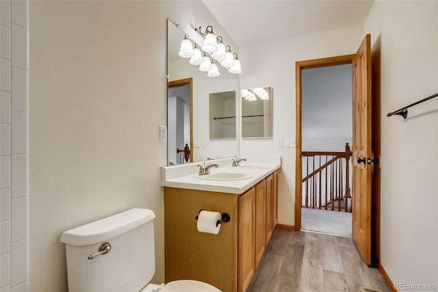 bathroom with toilet, double vanity, a sink, and wood finished floors