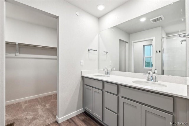 18998 E 94th Pl, Commerce City, CO 80022 - bathroom featuring a walk in closet, double vanity, a shower stall, and wood finished floors