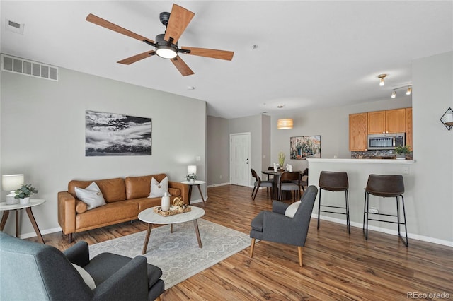 living room featuring ceiling fan and dark wood-type flooring