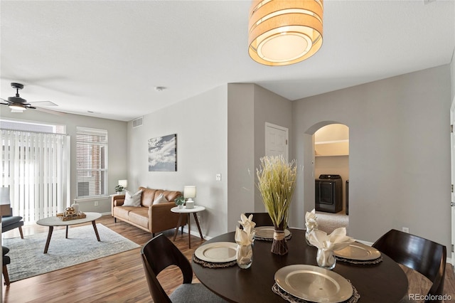 dining space featuring washer / clothes dryer, ceiling fan, and wood-type flooring