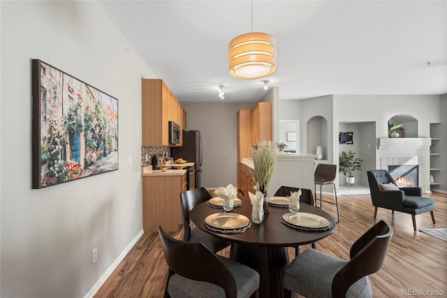 dining space with a fireplace, built in features, and light hardwood / wood-style flooring