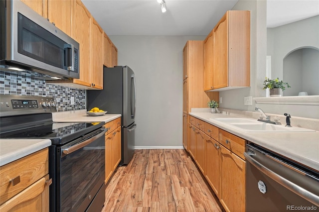 kitchen with stainless steel appliances, light hardwood / wood-style floors, tasteful backsplash, and sink