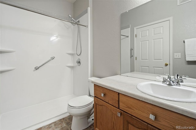 bathroom featuring toilet, a shower, and vanity