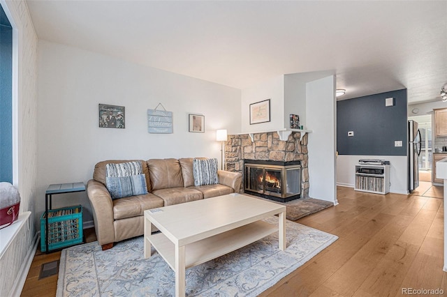 living room featuring visible vents, light wood-style flooring, and a fireplace