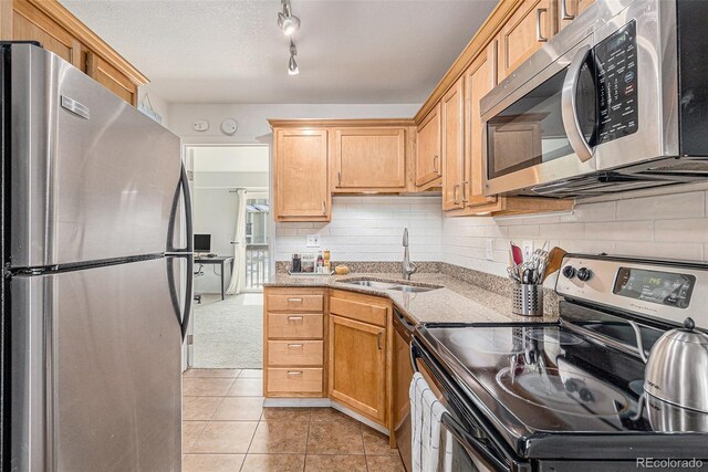 kitchen with tasteful backsplash, light tile patterned floors, light stone counters, stainless steel appliances, and a sink