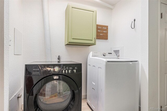 clothes washing area featuring cabinet space and washing machine and clothes dryer