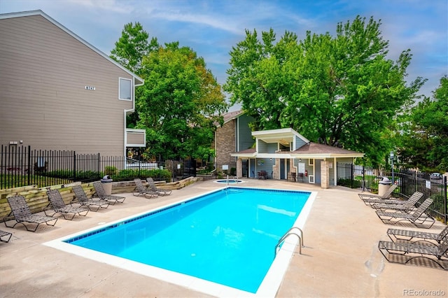 view of swimming pool with a patio, a hot tub, and an outbuilding