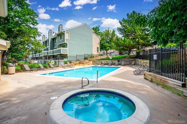 view of swimming pool featuring a patio and a hot tub