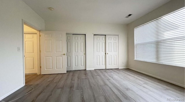 14333 E 1st Dr Unit 108, Aurora, CO 80011 - unfurnished bedroom with baseboards, wood finished floors, and two closets