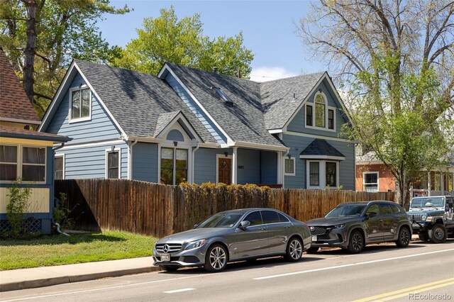 view of front facade with a shingled roof and fence