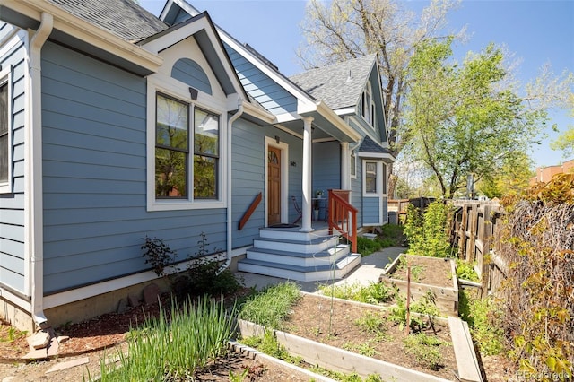 view of front of home featuring a garden, a shingled roof, and fence