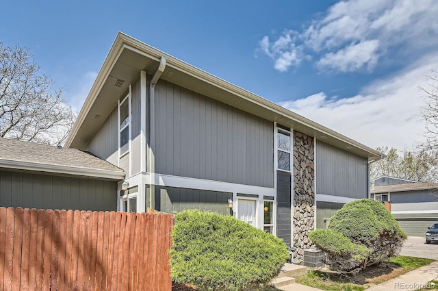 view of side of property featuring fence and stone siding