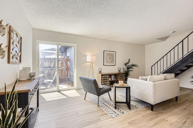 living room with wood finished floors, a textured ceiling, and stairway
