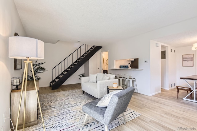 living area with stairway, wood finished floors, a textured ceiling, and baseboards