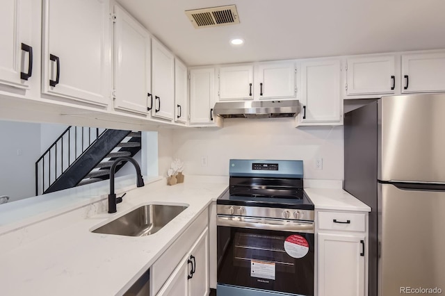 kitchen with appliances with stainless steel finishes, under cabinet range hood, a sink, white cabinets, and recessed lighting