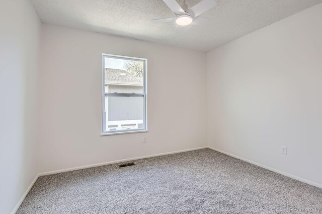 carpeted spare room with a ceiling fan, baseboards, and a textured ceiling