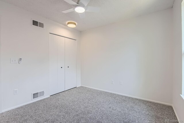 unfurnished bedroom with carpet flooring, baseboards, a closet, and a textured ceiling