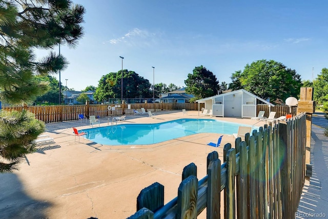 community pool with fence and a patio area