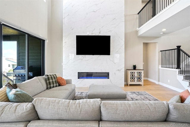 living room with a premium fireplace, a towering ceiling, and hardwood / wood-style flooring