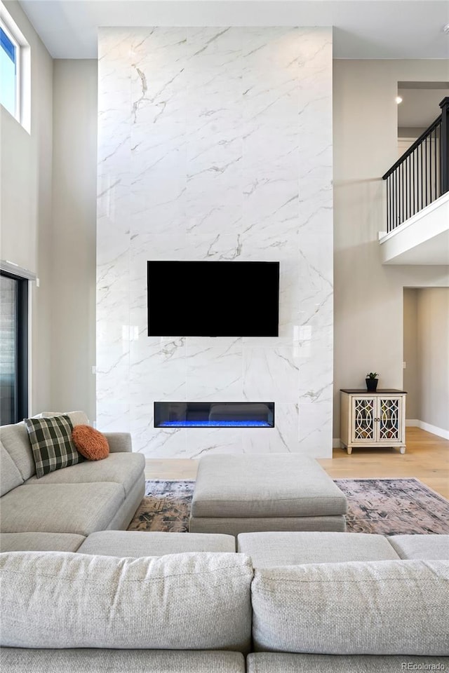 living room featuring a fireplace, a towering ceiling, and wood-type flooring