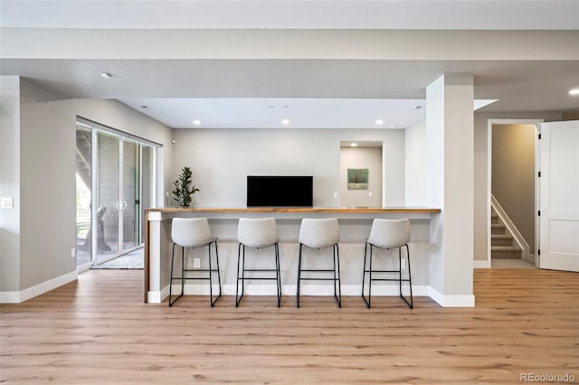 kitchen featuring a kitchen bar, light hardwood / wood-style floors, and kitchen peninsula