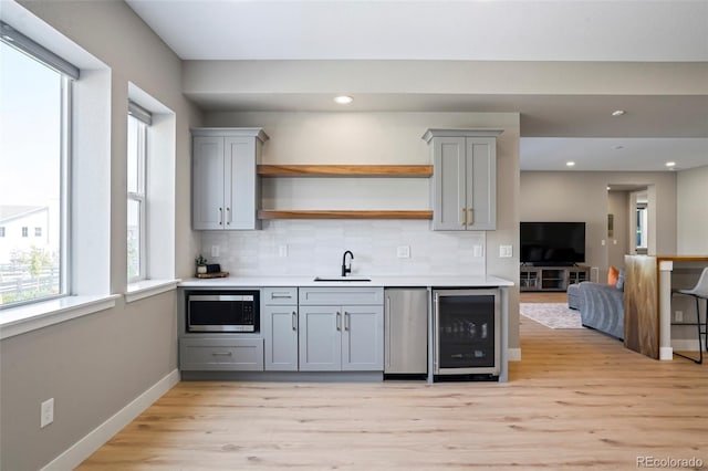 kitchen featuring light hardwood / wood-style flooring, stainless steel appliances, sink, gray cabinets, and beverage cooler