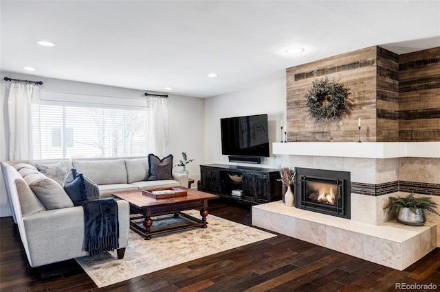 living room featuring a tile fireplace and dark hardwood / wood-style floors