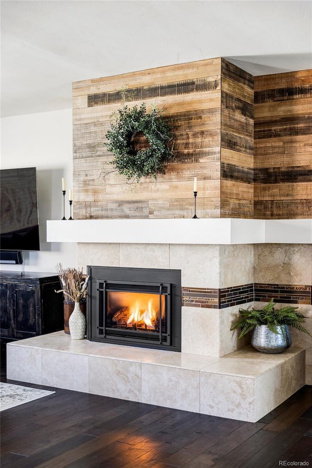 details with a tiled fireplace and wood-type flooring