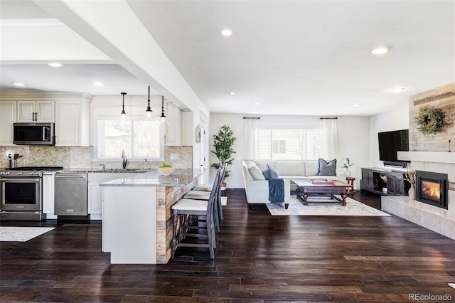 kitchen featuring light stone counters, a breakfast bar area, appliances with stainless steel finishes, and tasteful backsplash