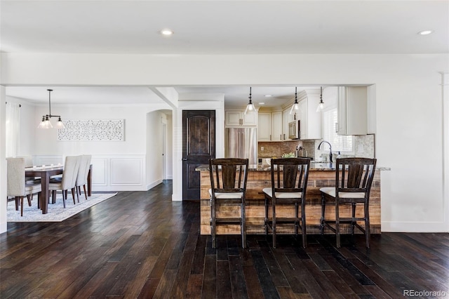 dining area featuring dark hardwood / wood-style flooring, sink, and a chandelier