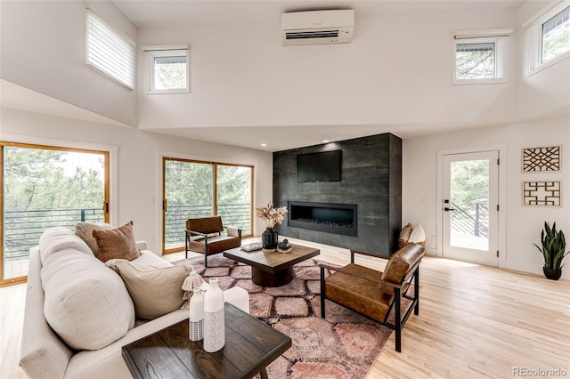 living room featuring a wall mounted air conditioner, a wealth of natural light, and light hardwood / wood-style floors