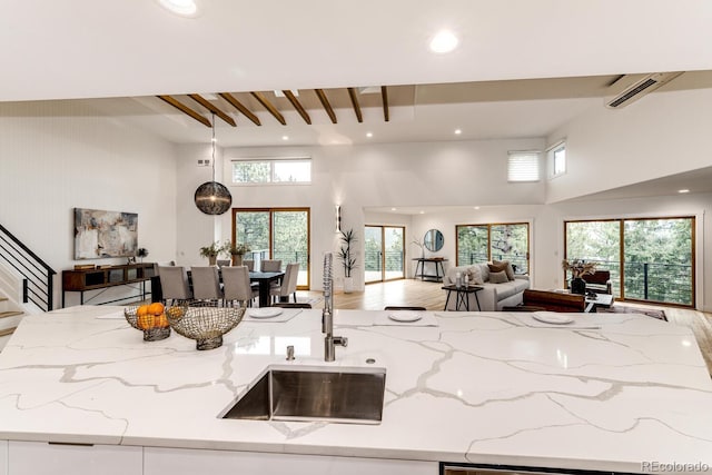 kitchen with light stone countertops, sink, a wall mounted AC, and plenty of natural light