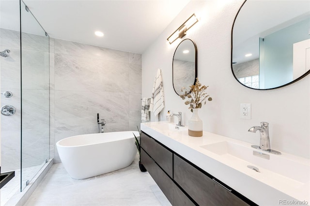 bathroom with shower with separate bathtub, tile walls, and vanity